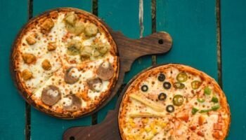 Food-Safe Wood Oil Two pizzas with various toppings on wooden boards over a rustic green table, captured in a top-down view.